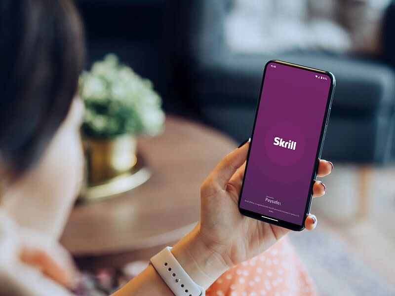 Image of person opening the Skrill app on their phone